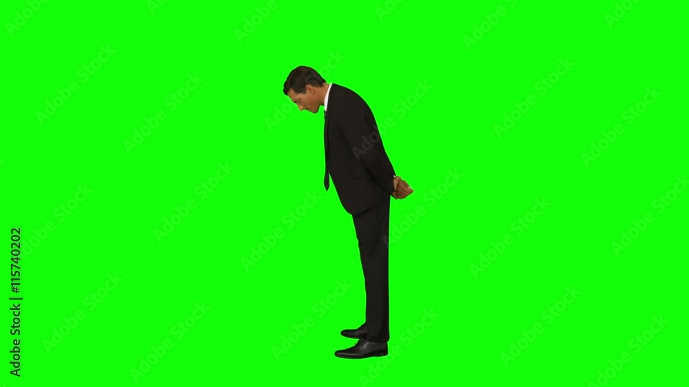 Businessman standing with hands behind back looking down Businessman standing with hands behind back looking down