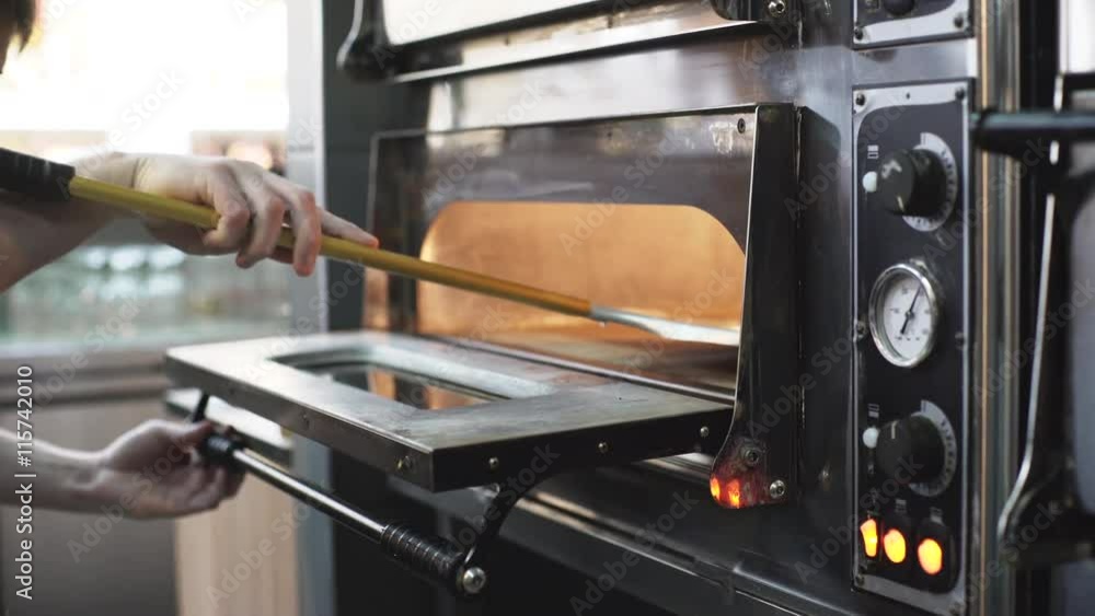 Cook puts a raw pizza into the oven Cook puts a raw pizza into the oven
