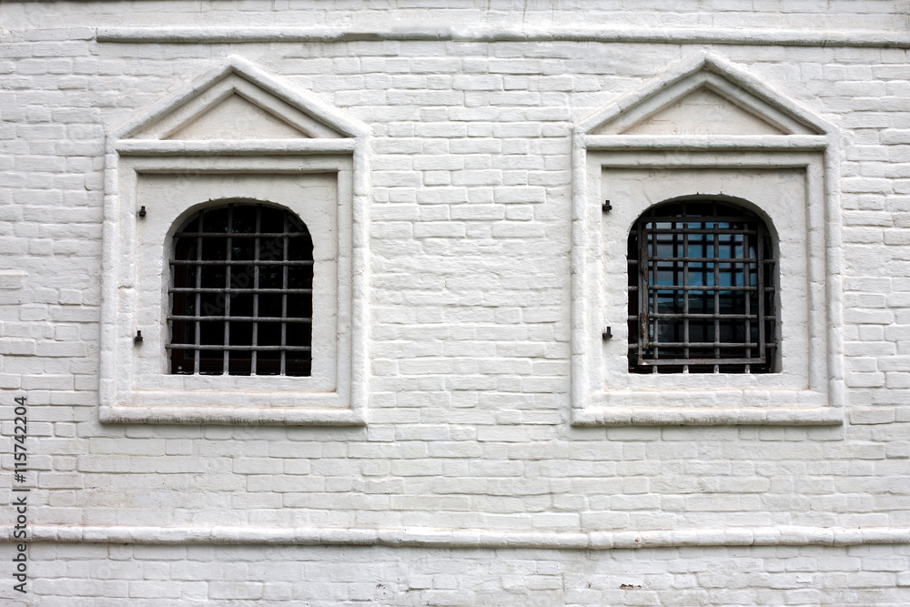 Two windows with bars in brick wall