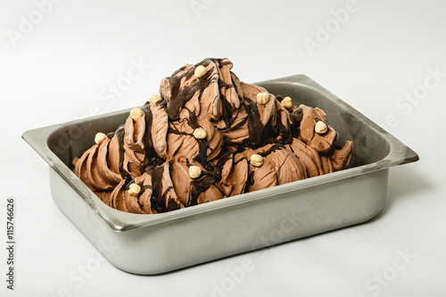 Chocolate ice cream with hazelnuts in the metal tray on white background
