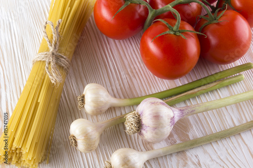Raw pasta and ingredients with tomatoes , garlic.