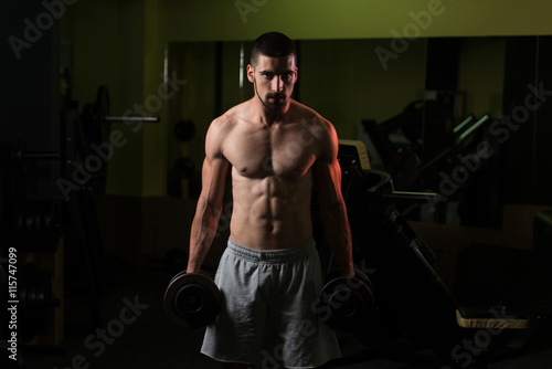 Man In The Gym Exercising Biceps With Dumbbell