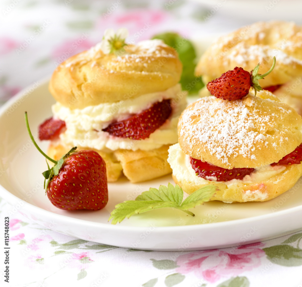 Cream puff cakes or profiterole filled with whipped cream, served with strawberries Cream puff cakes or profiterole filled with whipped cream, served with strawberries