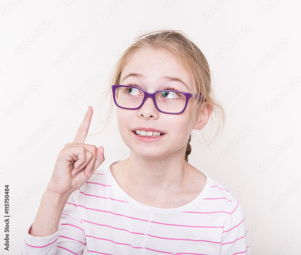Blond child girl in violet glasses pointing finger up.