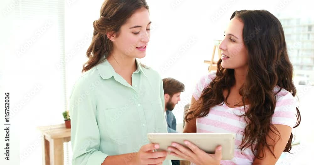 Two casual businesswoman using tablet computer and looking at camera Two casual businesswoman using tablet computer and looking at camera