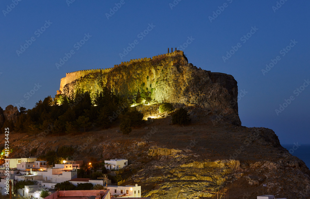 Medieval fortifications atop a rock in Lindos at night.