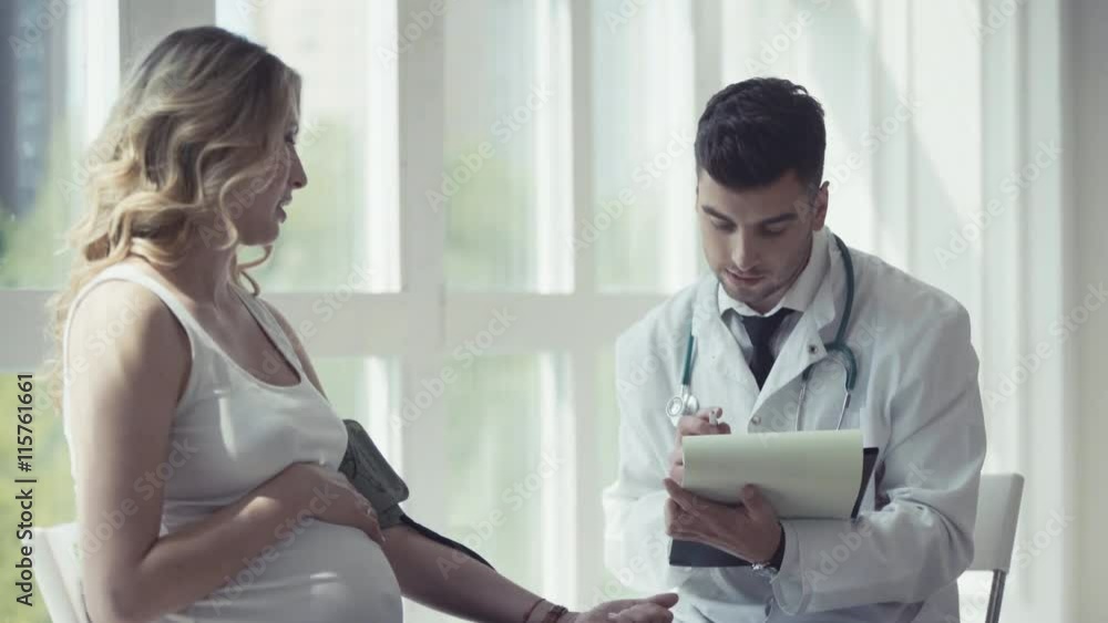 Young doctor checking blood pressure of a pregnant woman Young doctor checking blood pressure of a pregnant woman