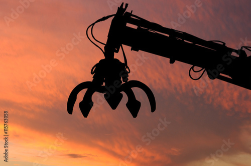 Tablou Canvas Clamshell and Hydraulic crane shillouette with evening light sky