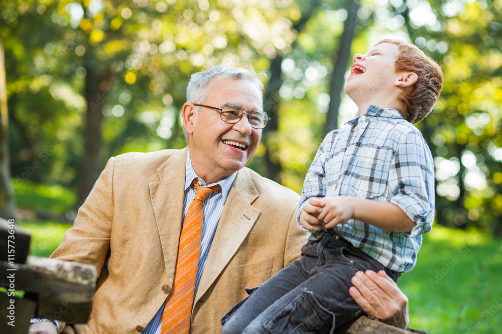 Grandfather and grandson are sitting and talking in park Grandfather and grandson are sitting and talking in park