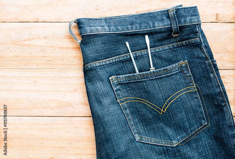 the jeans and screwdriver tool in pocket on wooden board the jeans and screwdriver tool in pocket on wooden board