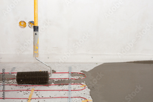 Electric floor heating system installation in new house. Closeup of the rooler for align concrete photo