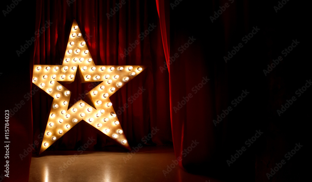 Fotografie, Obraz Photo of golden star with light bulbs on red velvet curtain on stage