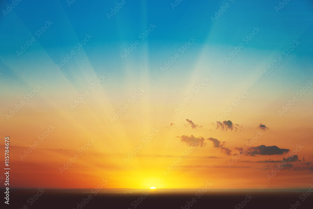 Obraz premium Beautiful blazing sunset landscape at over the meadow and orange sky above it. Amazing summer sunrise as a background.