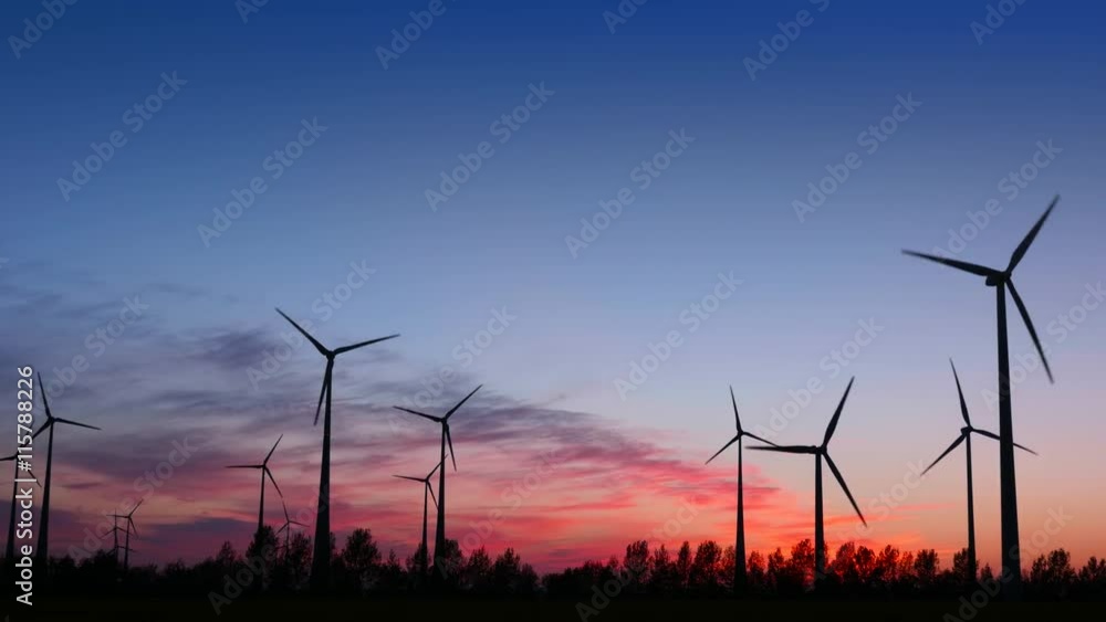 Wide shot of wind turbines right after sunset.
