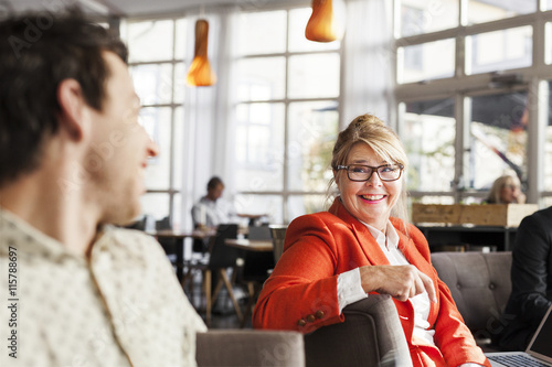 Happy business people discussing while sitting at restaurant