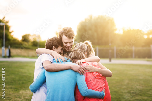 Sporty friends stacking hands in huddle at park during sunset