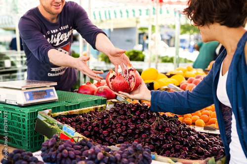 Vendor giving pomegranate to girl at market photo