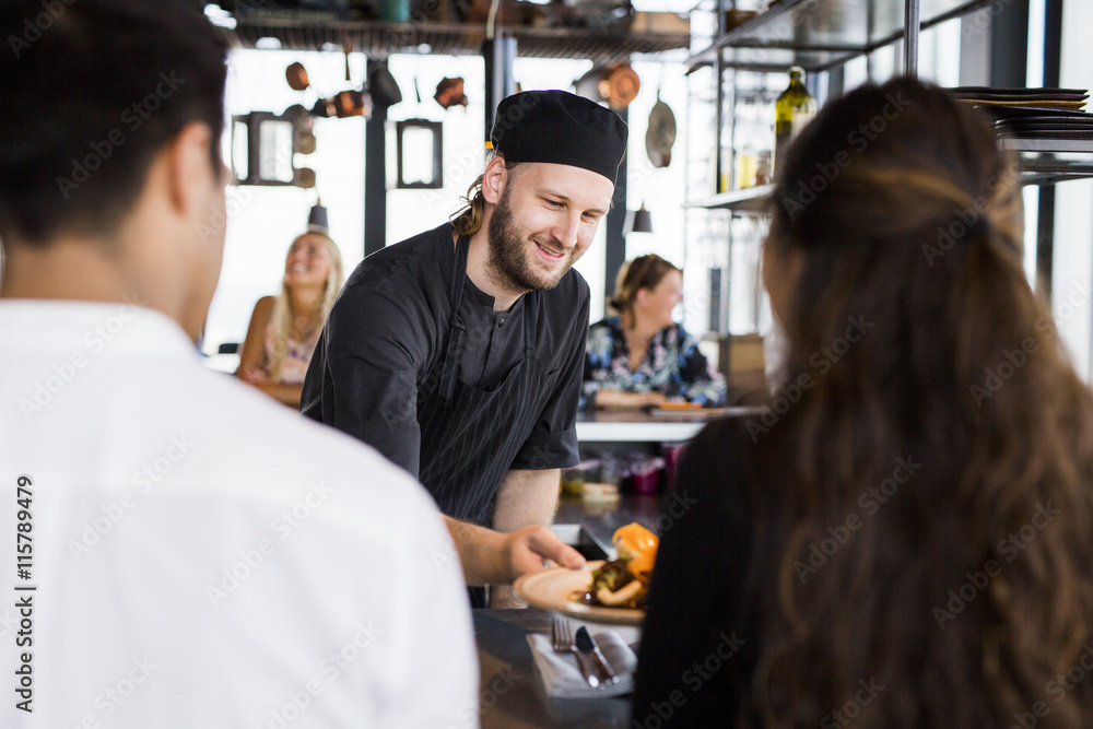 Happy chef serving dish to customers at Skybar restaurant Happy chef serving dish to customers at Skybar restaurant