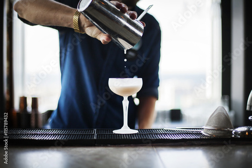 Bartender pouring cocktail from shaker into glass