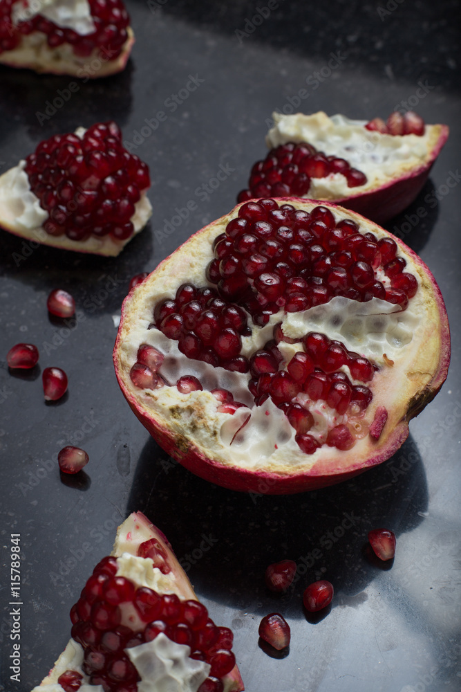 Red juicy pomegranate on dark marble background. Healthy, antioxidant, fresh, gourmet, delicious, organic fruit. Ingredient for grenadine. Close-up and copy space.
