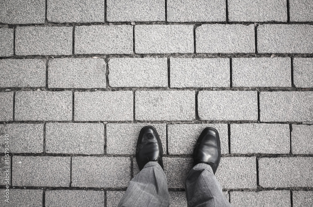 Male feet standing on gray cobblestone road Male feet standing on gray cobblestone road