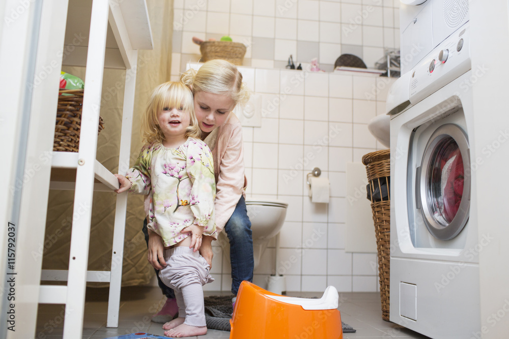 Girl helping younger sister in toilet Stock Photo | Adobe Stock