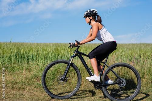 Young lady with bicycle on a spring meadow