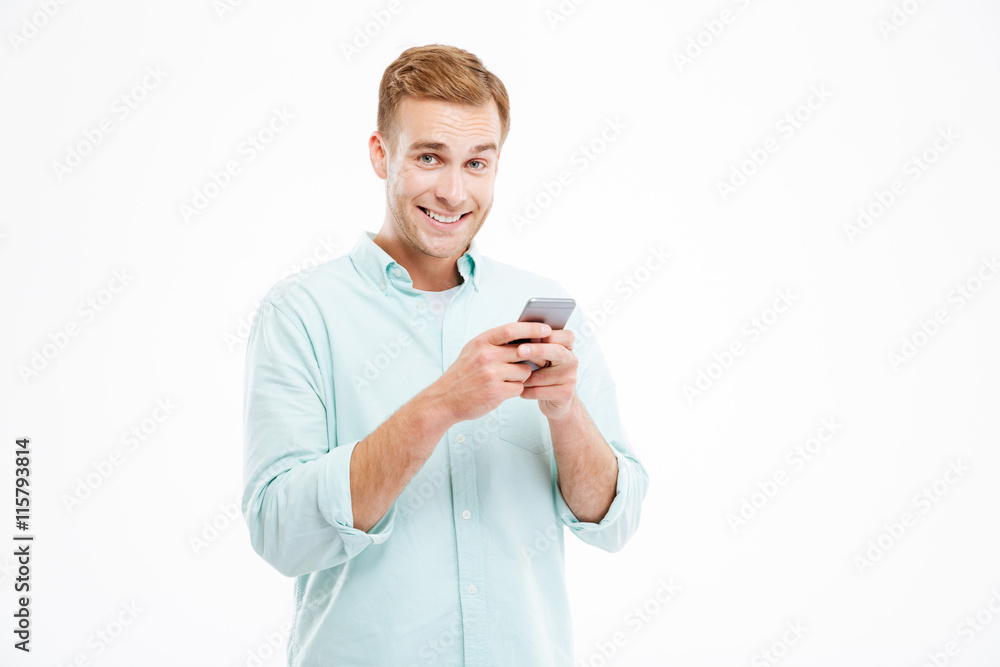 Cheerful handsome young businessman standing and using smartphone