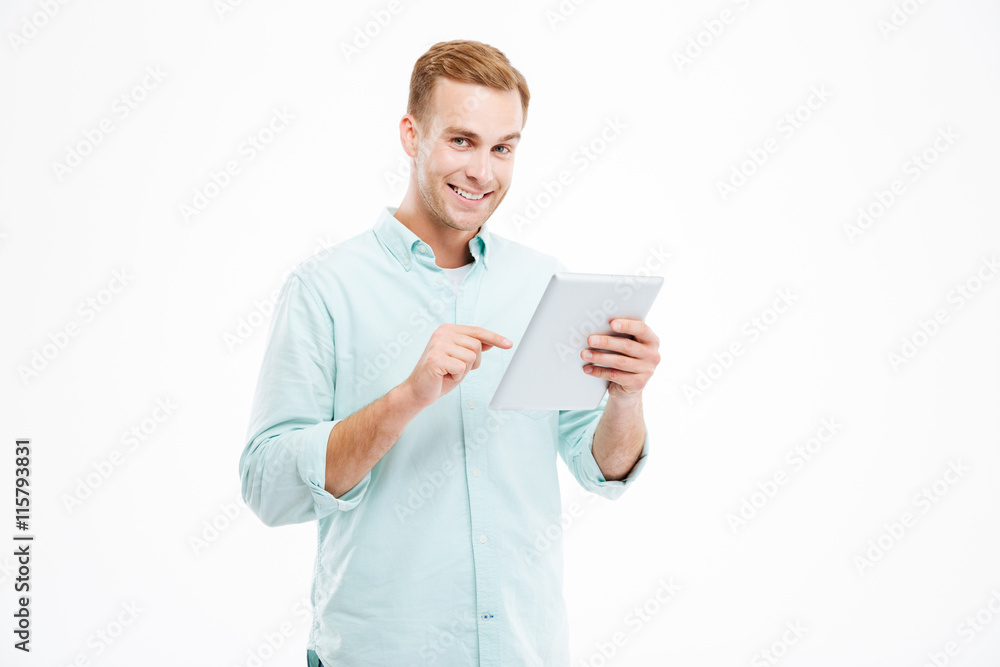 Happy handsome smiling young guy using tablet Happy handsome smiling young guy using tablet