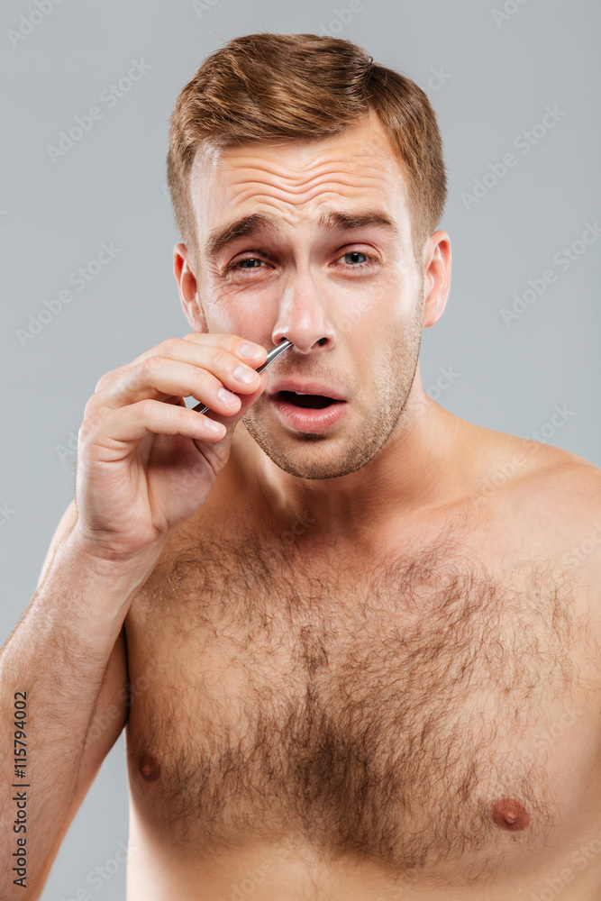 Obraz premium Close-up portrait of man removing nose hair with tweezers