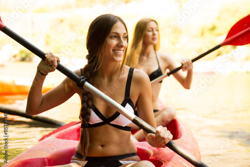 Two girls doing kayaking in a river with a canoe © kikearnaiz