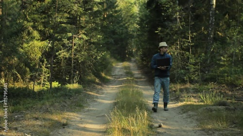 Wallpaper Mural A man walks through the forest with a laptop and looking map He chooses the right direction Torontodigital.ca