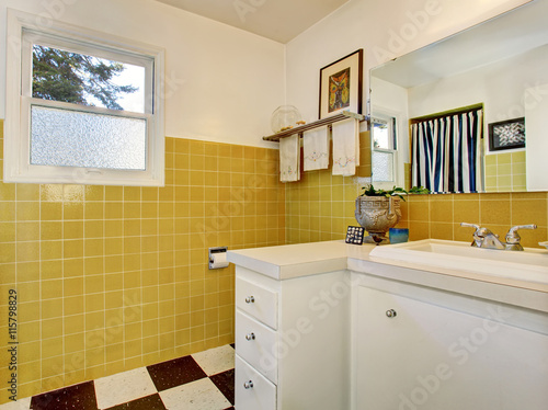Bathroom interior with white cabinet  yellow tile on the walls and small window.