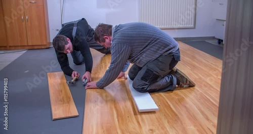 Wallpaper Mural Two handymen are building wood flooring and they're making sure that everything is even using a hammer. Then they stand up.
 Torontodigital.ca