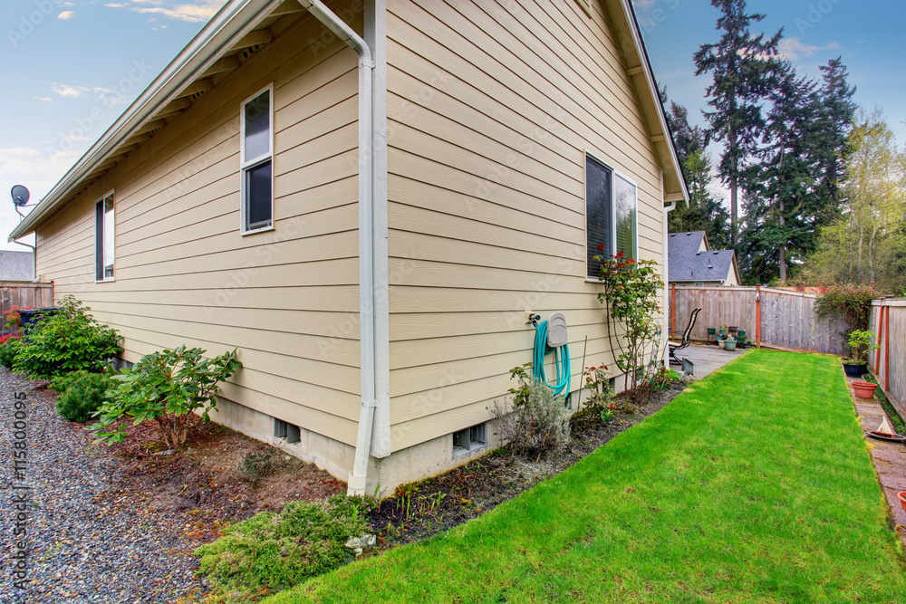 Obraz premium House exterior with beige siding. Fenced Back yard with green lawn.