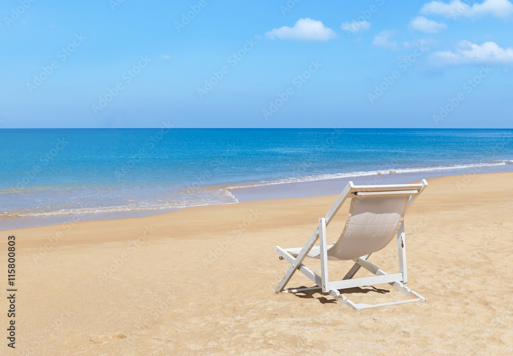 Empty white wooden beach chair on tropical beach with blue sky 
