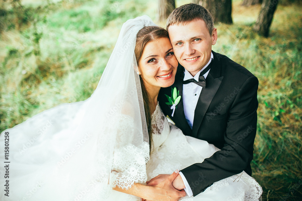 Young wedding couple enjoying romantic moments outside on a summer meadow. Copy space. Pine forest. Green forest are kissing photo portrait. Bride and groom Young wedding couple enjoying romantic moments outside on a summer meadow. Copy space. Pine forest. Green forest are kissing photo portrait. Bride and groom