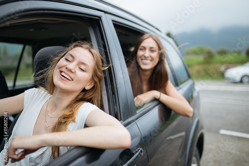 Young and beautiful girls having fun in the window of a car.