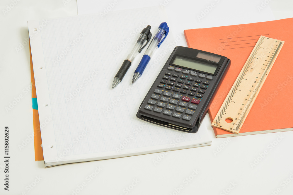 The concept of learning shown with a calculator & pens on a background of graph paper The concept of learning shown with a calculator & pens on a background of graph paper