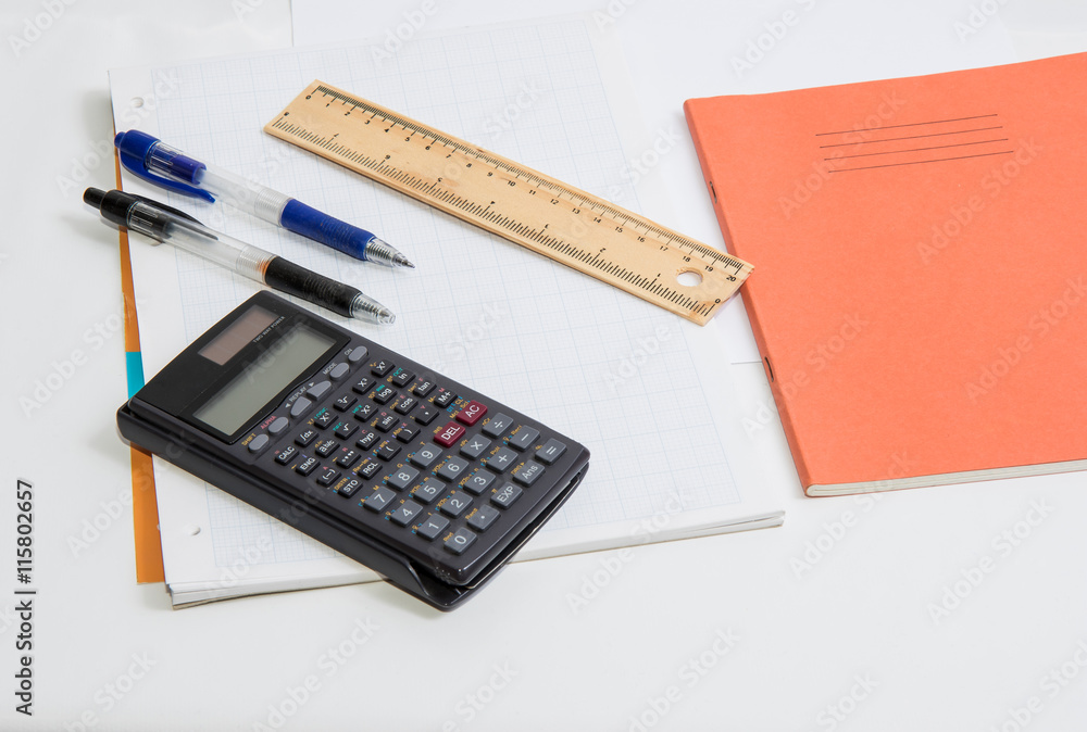 The concept of learning shown with a calculator & pens on a background of graph paper The concept of learning shown with a calculator & pens on a background of graph paper