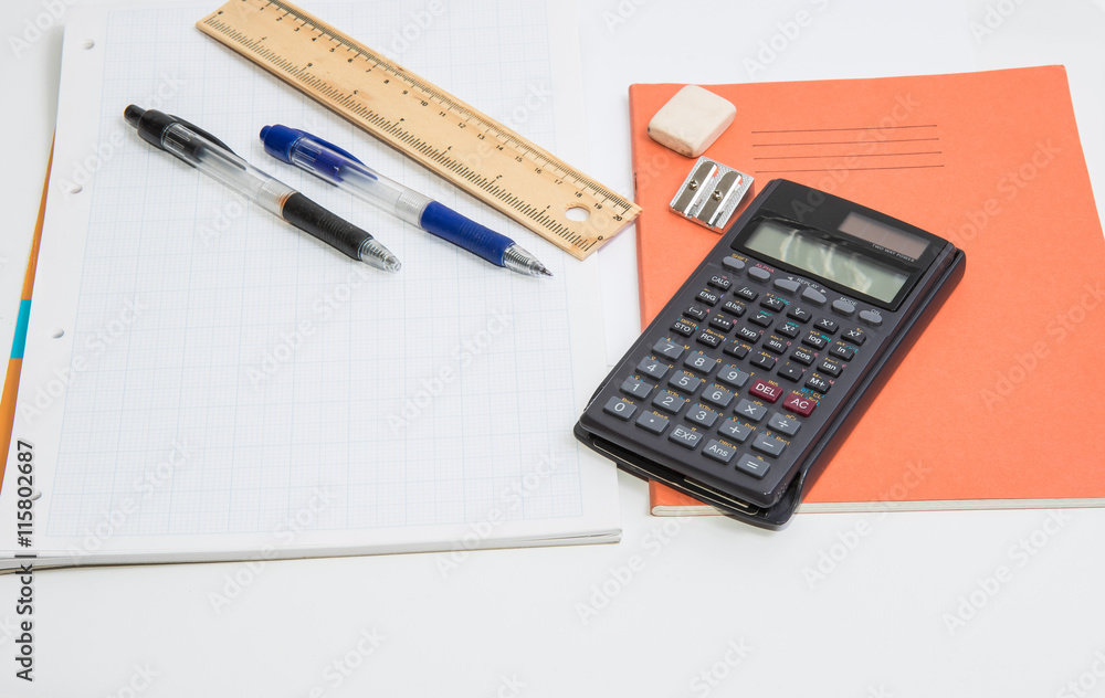 The concept of learning shown with a calculator & pens on a background of graph paper The concept of learning shown with a calculator & pens on a background of graph paper