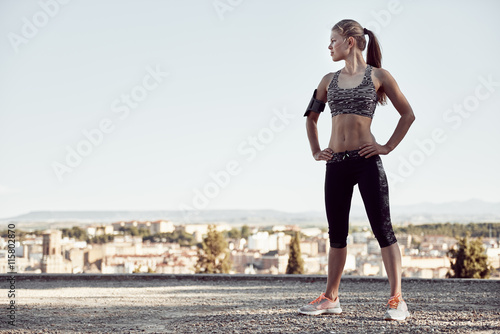 Beautiful fitness girl in sportswear resting after workout session standing on rocky road outside. Concept of sport, wellness and health. 