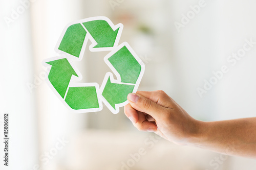 close up of hand holding green recycle symbol