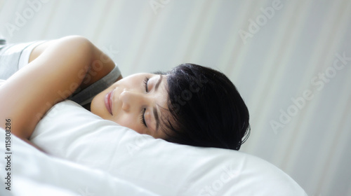 Woman sleeping happily in bed in the morning sunlight
