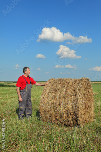Farmer and bale of hay in field
