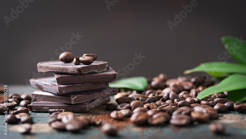 Stack of chocolate chunks with coffee beans on a wooden background, horizontal with copy space