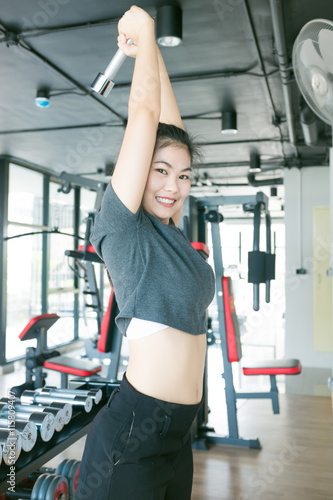 Work out concept asian female holding barbells in modern fitness