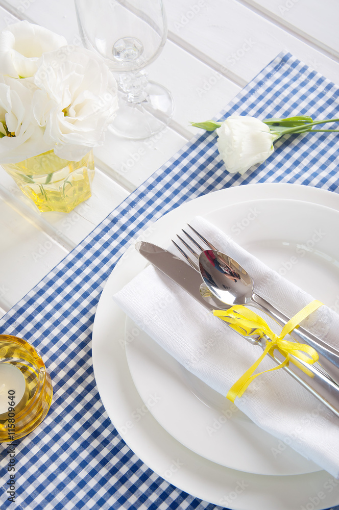 Table setting with blue checkered tablecloth, white napkin 