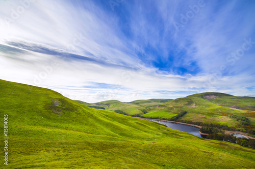 Landscape scenery of green valley, hill, river and cloudy blue sky