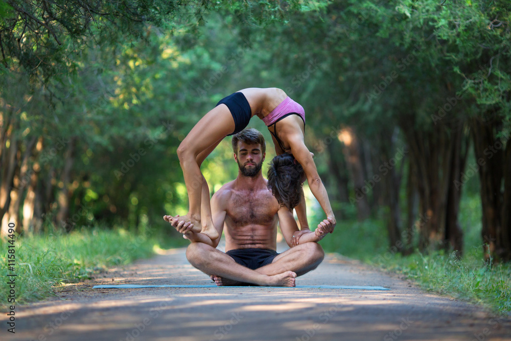Fotografia Acro yoga, two sporty people practice yoga in pair, couple doing  stretching exer - Kup na